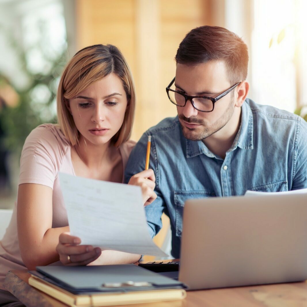 Portrait of young couple calculating budget at home.